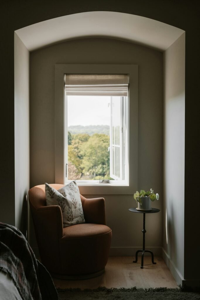 Neutral country reading nook with an armchair and warm layered lighting